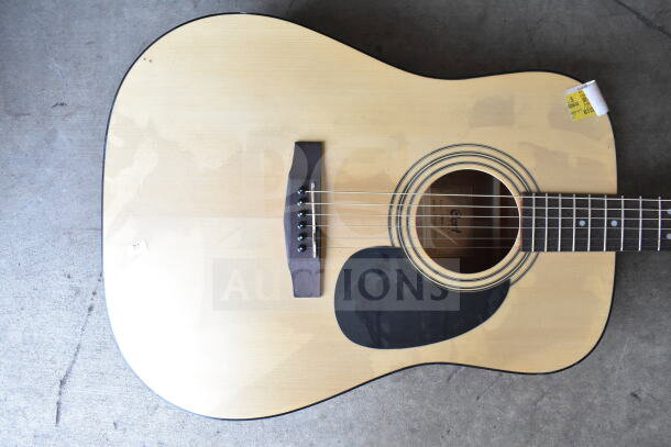 Cort acoustic guitar in natural finish with dark pickguard. Visible Cort label inside soundhole. Good condition.