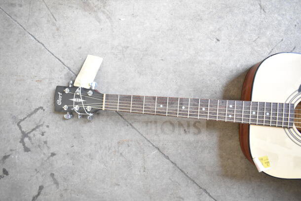 Cort acoustic guitar with natural finish, visible headstock and fretboard, good condition, price tag attached.