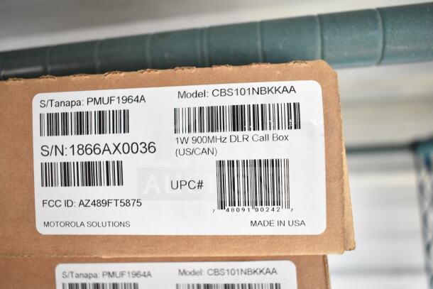 Cardboard box showing labels: Model CBS101NBKKAA, 1W 900MHz DLR Call Box, S/N: 1866AX0036, FCC ID: AZ489FT5875, by Motorola Solutions. Made in USA.