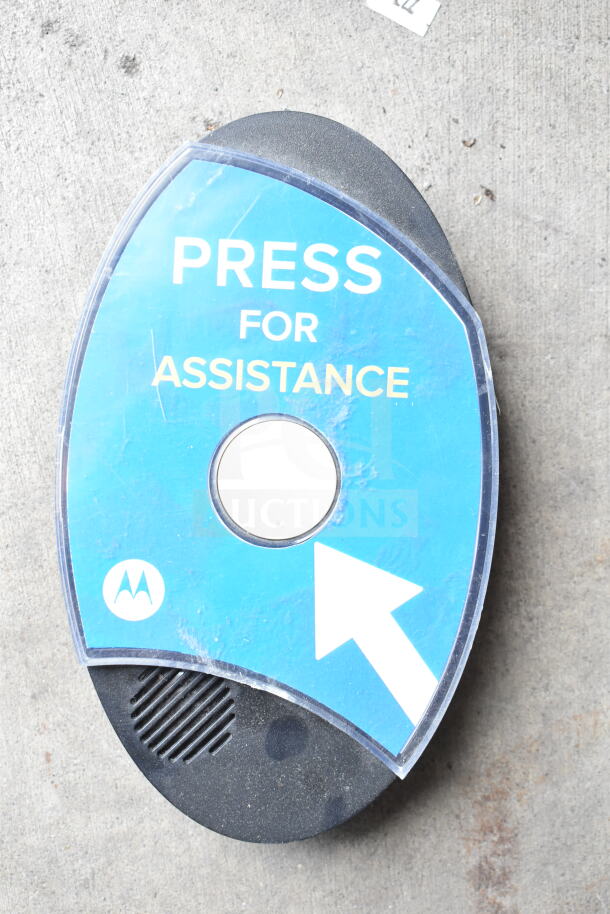 Motorola digital callbox with "Press for Assistance" text, blue faceplate, and speaker grille, showing wear.