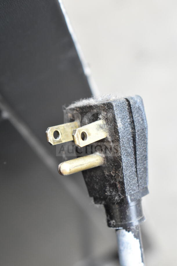 Close-up of a commercial cooler power plug for True GDM-33-LD, showing a slightly worn black prong.