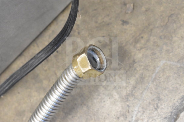 Close-up of a gas connection fitting for a Wolf Commercial Countertop 8 Burner Range. Rust-free with a brass nut and flexible hose.