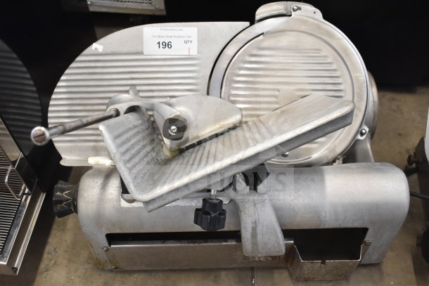 Commercial countertop meat slicer with metal body. Powered by 115 volts, 1 phase. Auction label visible.