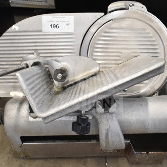 Commercial countertop meat slicer with metal body. Powered by 115 volts, 1 phase. Auction label visible.