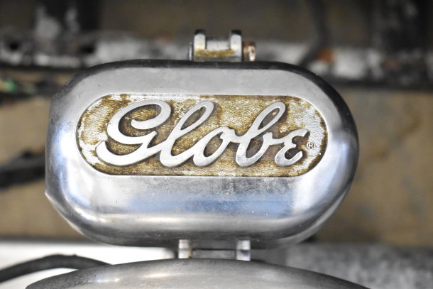 Globe 500 meat slicer with attached blade sharpener, showing brand logo. Operates at 115 volts, 1 phase.