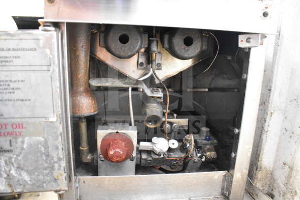 Countertop gas-powered deep fat fryer interior, metal casing, visible controls, and machinery, shows signs of wear.