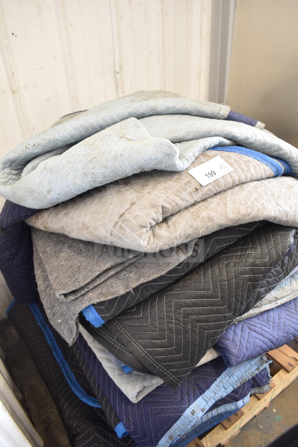 Set of 14 used moving blankets in various colors, stacked on pallet. Quilt pattern, visible tag marked "199".