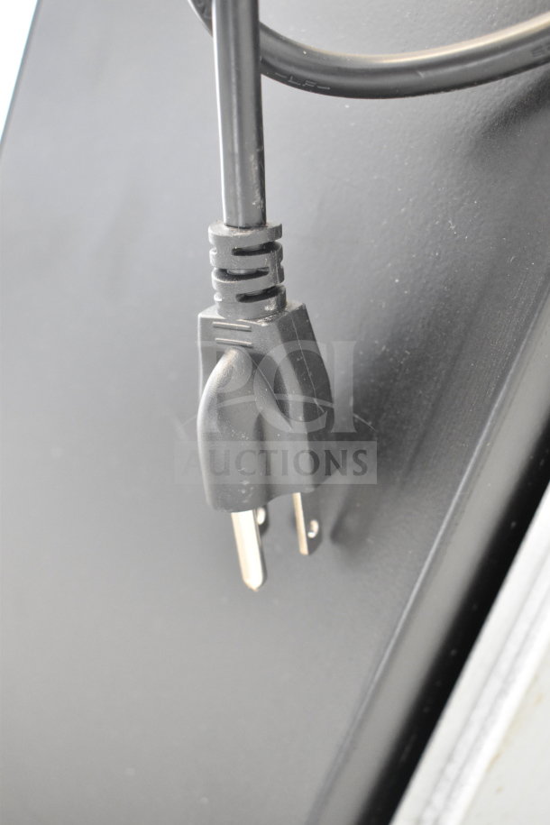 "Air Curtain, 115V, 1 Phase. Close-up of the power plug, in good condition, attached to the black body of the device."
