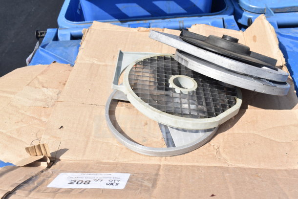 Five assorted food processor blades on cardboard, featuring grid patterns and circular designs. Condition appears used.