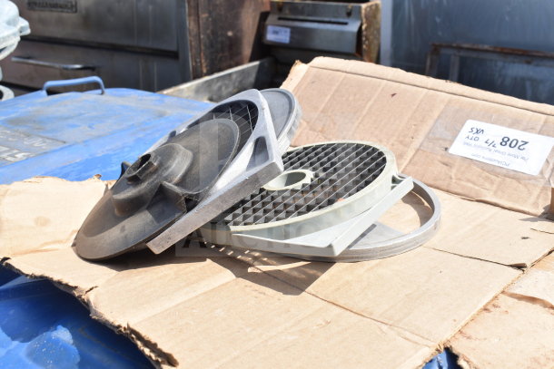 Five various food processor blades on cardboard, showing wear. Includes discs and grid types for versatile processing.