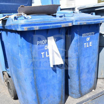 Two large blue poly trash cans labeled "Property of TLE," in used condition, with wheels for mobility.