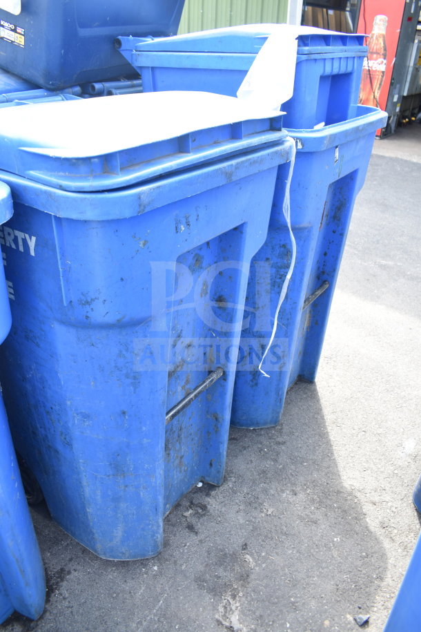 Three blue poly trash cans, used condition, on pavement. Features handles and lids. Sturdy build, ideal for waste management.