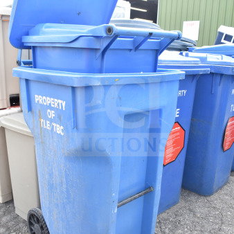 Three blue poly trash cans, marked "Property of TLE/TBC," with wheels and lids; weathered condition.