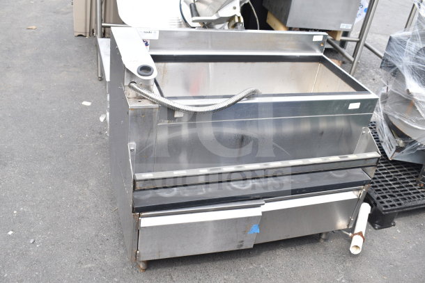 Commercial ice bin, stainless steel, used condition, features drainage hose and storage compartment, visible surface wear.