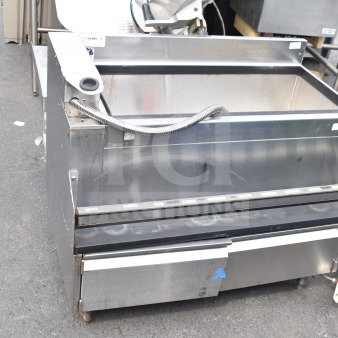Commercial ice bin, stainless steel, used condition, features drainage hose and storage compartment, visible surface wear.