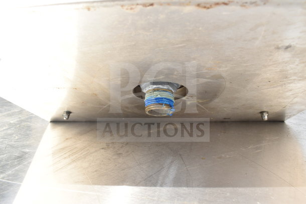 Stainless steel drop-in sink bay with visible plumbing and mounting hardware, in used condition.