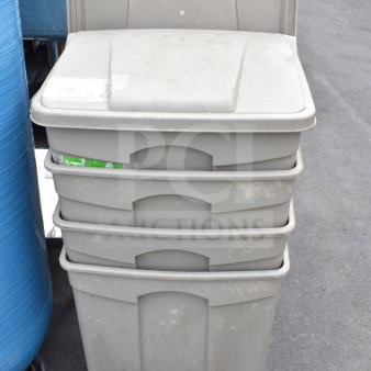 Four tan poly trash cans stacked, featuring pedal operation and visible wear. Ideal for bulk purchase auction.