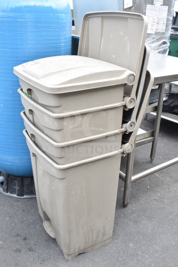 Four stacked tan poly trash cans in used condition, each with lids, suitable for outdoor or indoor use.