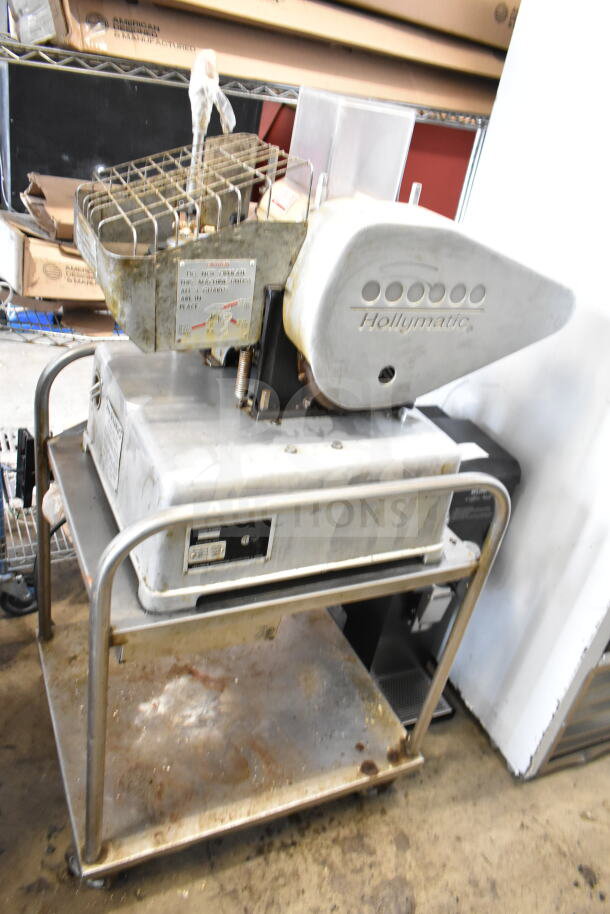Hollymatic commercial patty former machine on cart, 115 volts, 1 phase, visible wear, branded markings on side.