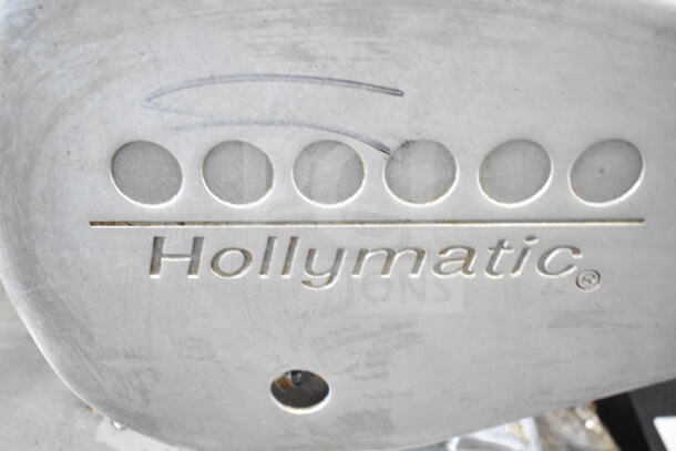 Hollymatic logo close-up on a stainless steel surface, part of a commercial patty former machine.