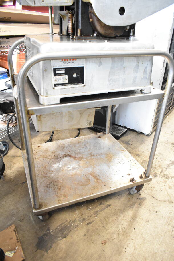 Hollymatic commercial patty former machine on a cart, 115 volts, 1 phase. Shows wear. Label indicates model and specs.