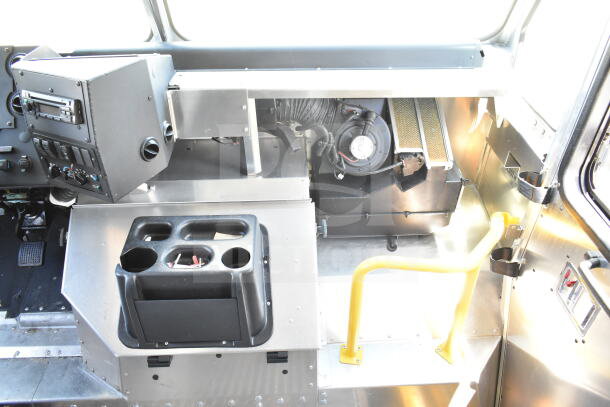 Interior of 2021 Ford Step Van, featuring a control panel, cup holders, and metal steps with a yellow handrail.