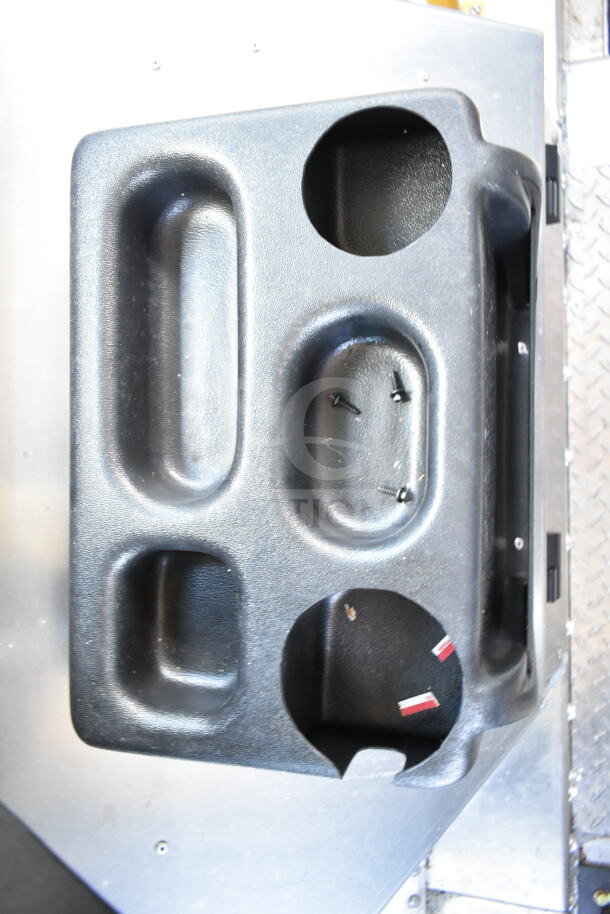 2021 Ford Step Van interior detail, featuring molded plastic door panel with cup holders, switches, and screws visible.