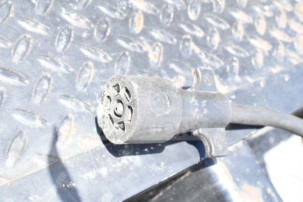 Close-up of a connector plug on a 2020 Southern Dimensions 8.5x28 Cold Beverage/Food Trailer. Rugged, metal surface background.