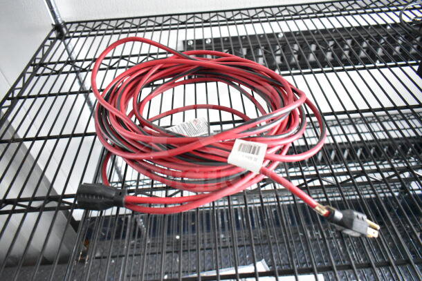 Coiled red and black extension cord on a metal shelf, showing a plug and a visible label with barcode.