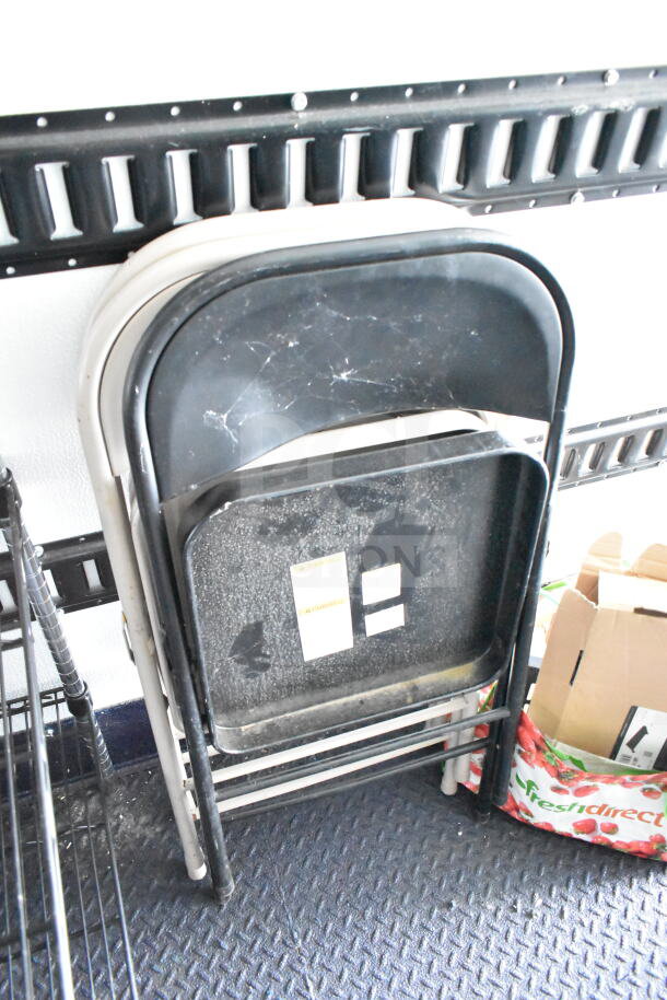 Stacked folding chairs inside a trailer. Chairs show signs of wear with visible scuffs and scratches.
