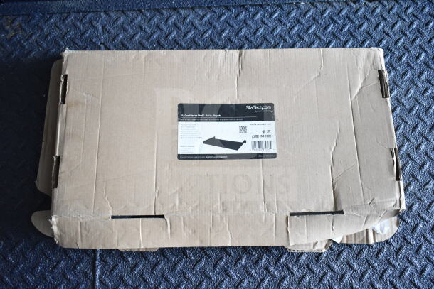 Cardboard box containing a StarTech 1U cantilever shelf. Label indicates 10 in. depth, Part Number: CABSHELF1U10. Box slightly worn.