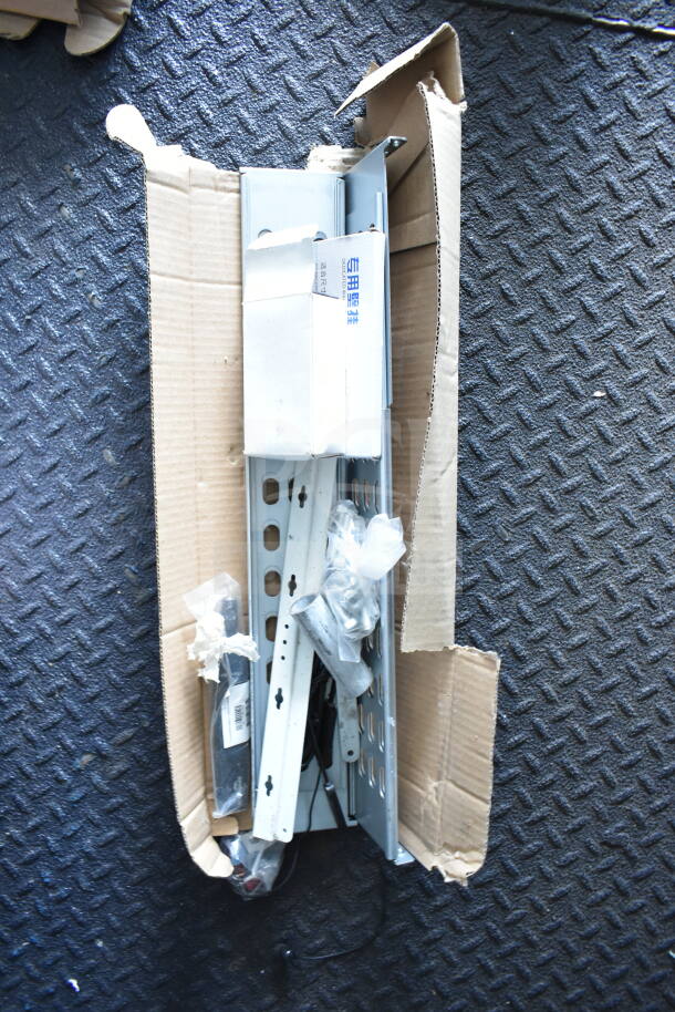 Open box of metal brackets and hardware for Southern Dimensions trailer, new condition, partially wrapped in bubble wrap.