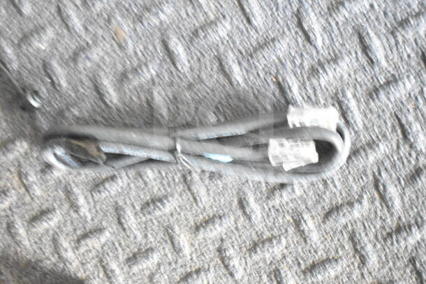 A coiled power cord with connectors on both ends lies on a carpeted floor, possibly a part of the trailer's accessories.