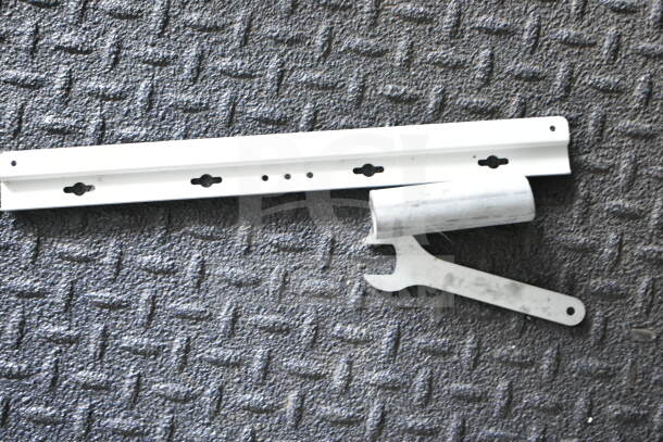 Metal bracket with mounting holes and a metal wrench tool on textured surface.