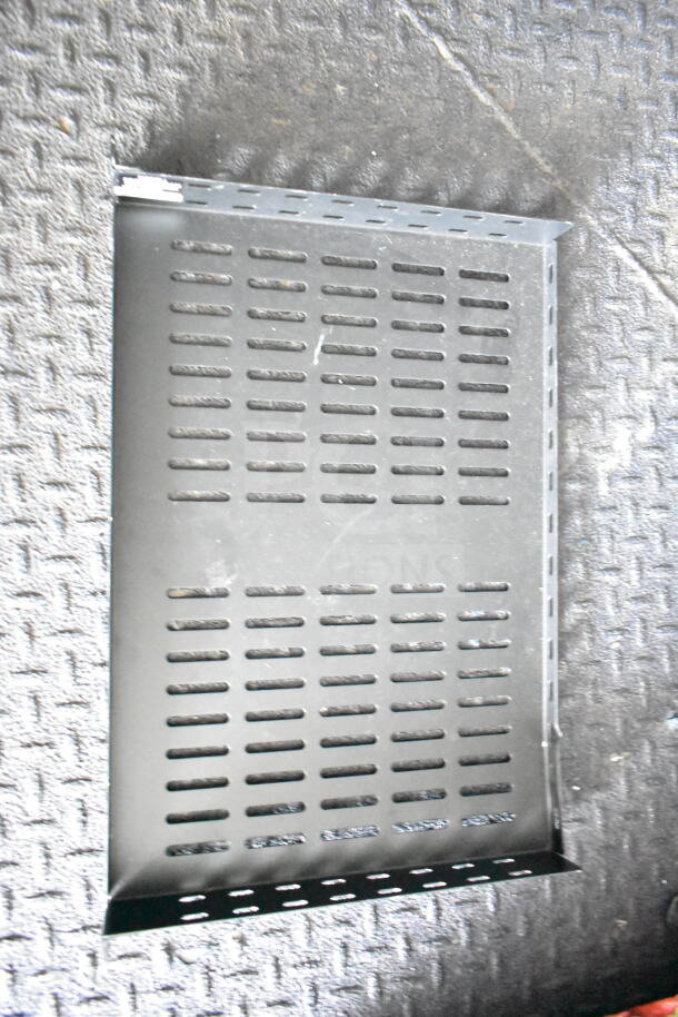 Metal vented shelf on a textured floor, used for cooling and storage, showing slight wear.