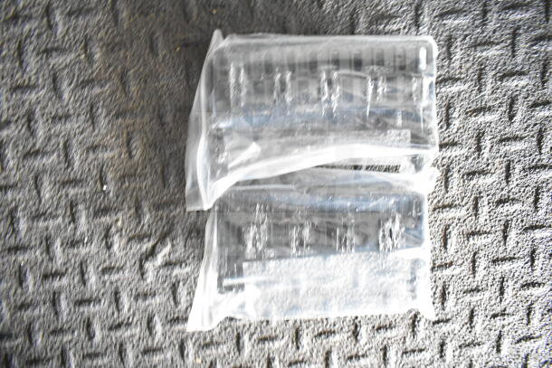 Two sealed automotive parts on a textured surface, wrapped in clear plastic packaging.