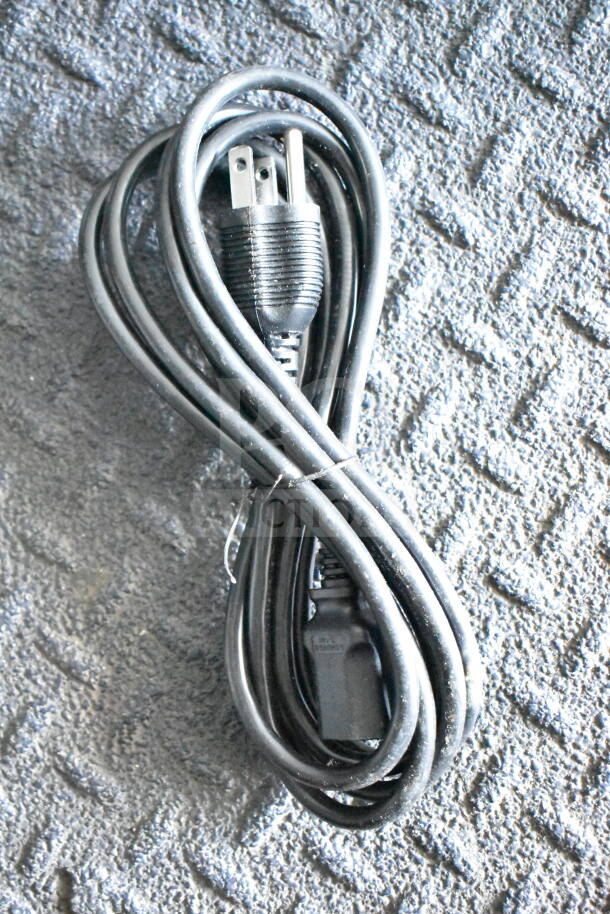 A coiled black power cord on a textured gray surface.