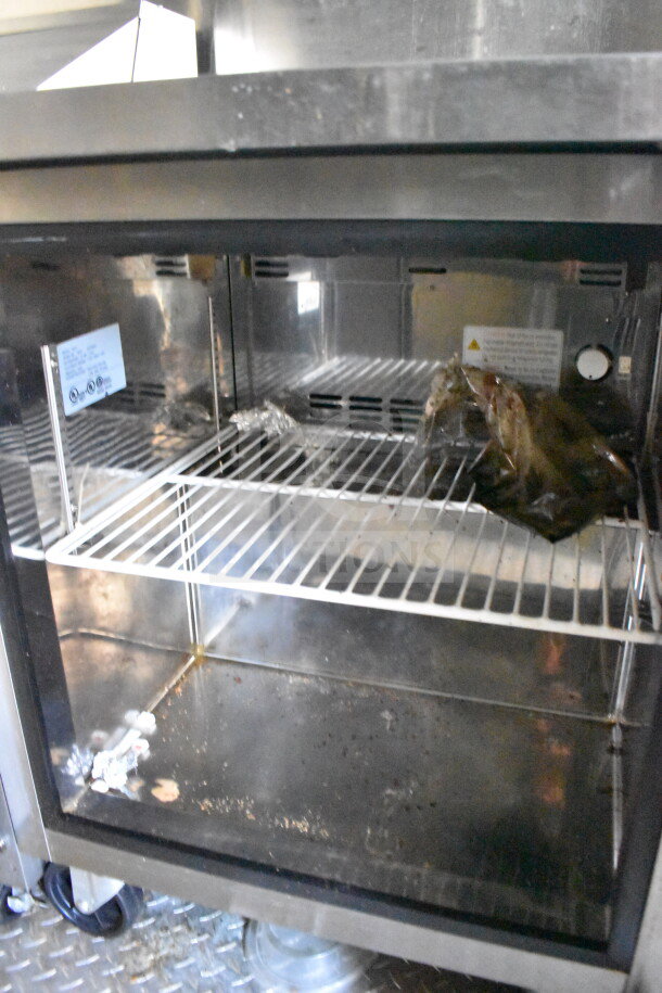 Interior of 2021 Diamond Cargo food trailer, showing a metal wire shelf and interior cooking equipment.