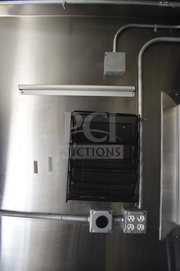 Interior view of a 2021 Diamond Cargo 8.5x24 food trailer showing electrical outlets, conduit, and a wall-mounted mesh organizer.