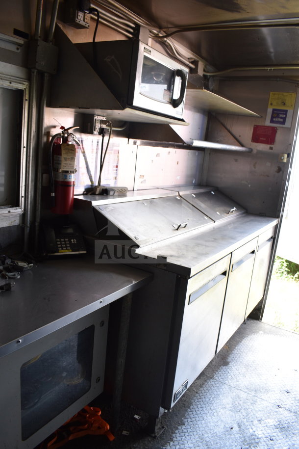 2020 Diamond Cargo 8.5x24 food trailer interior with stainless steel counters, shelving, fire extinguisher, and microwave.