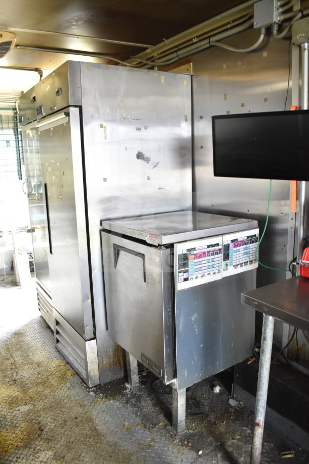 2020 Diamond Cargo 8.5x24 food trailer interior, featuring stainless steel appliances, shelving, and mounted monitor; gently used.