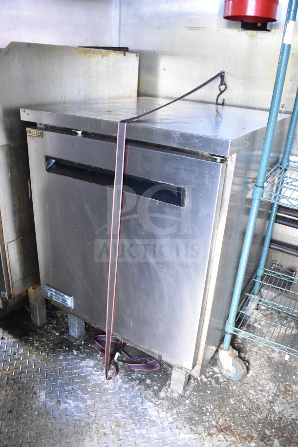 2020 Diamond Cargo 8.5x24 food trailer interior, featuring a stainless steel freezer on a non-slip floor, secured by a strap.