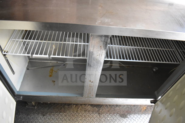 Inside view of a 2020 Diamond Cargo food trailer refrigeration unit with open doors, metal shelves, and visible residue.