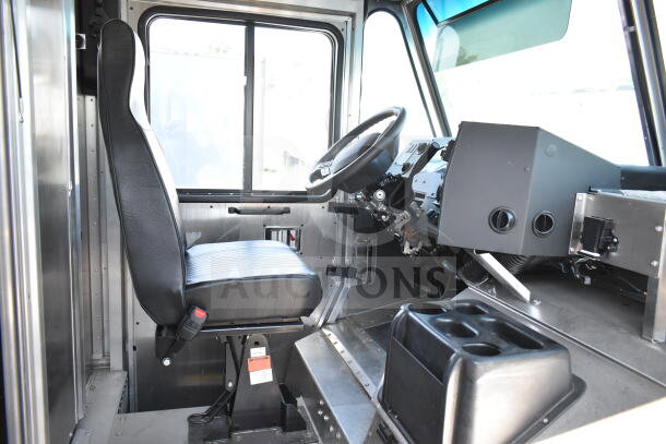 Interior of 2020 Ford F59 food truck, showcasing the driver’s seat, steering wheel, and dashboard controls in good condition.