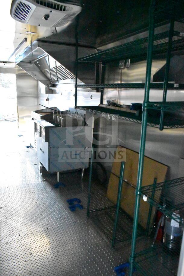 2020 Ford F59 food truck interior, showcasing kitchen setup with stainless steel appliances, shelving, and ventilation.