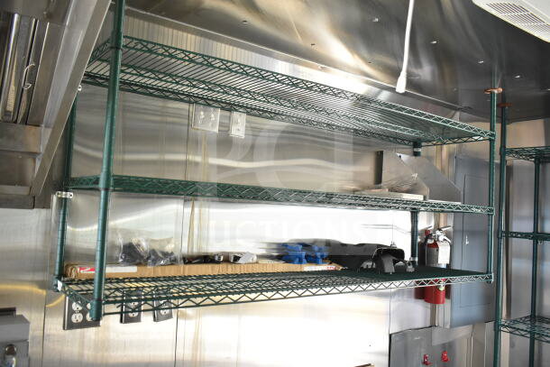 Interior of 2020 Ford F59 food truck with metal shelving, grease hood, suppression system, and fire extinguisher visible.