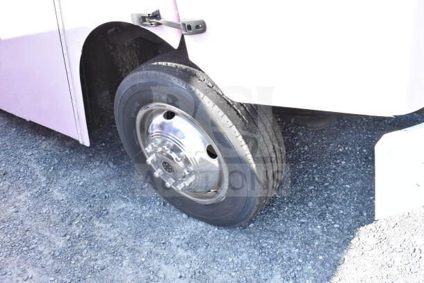 Wheel of 2020 Ford F59 food truck, Goodyear tire, chrome hubcap, showcased on gravel surface.