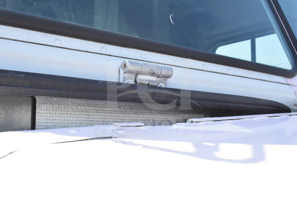 Close-up view of a 2020 Ford F59 food truck window, showing hinge detail, part of a larger auction listing.