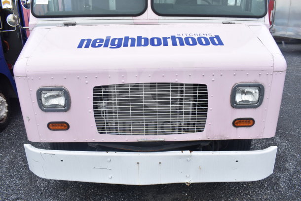 Front view of a pink 2020 Ford F59 Electric Food Truck with "neighborhood kitchens" branding, never used.