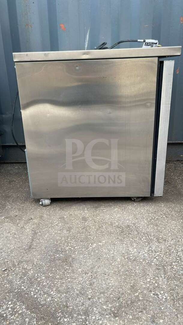True TUC-27-HC undercounter refrigerator, stainless steel, 27 5/8" width, visible wear, on casters, model label on top.